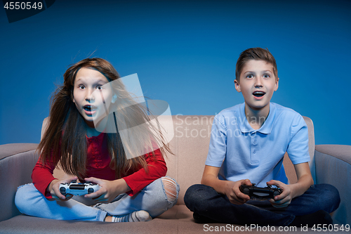 Image of Computer game competition. Gaming concept. Excited girl playing video game with joystick