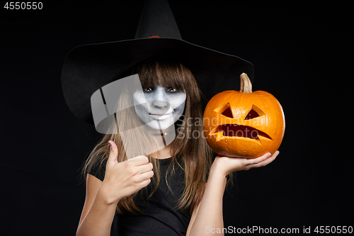 Image of Halloween witch girl showing Jack-O-Lantern pumpkin on palm