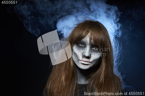 Image of A girl with zombie makeup over dark background with smoke and backlight