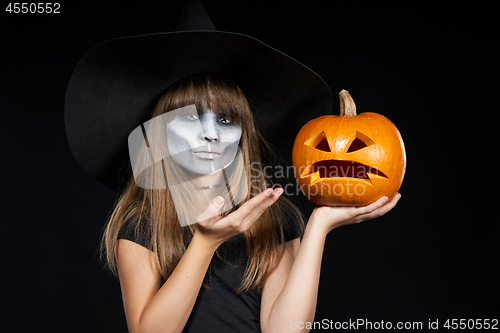 Image of Halloween witch girl showing Jack-O-Lantern pumpkin on palm