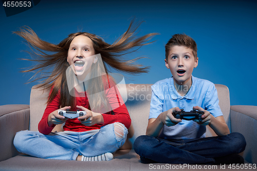 Image of Computer game competition. Gaming concept. Excited girl playing video game with joystick