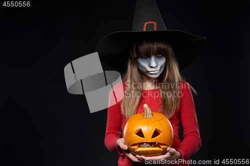 Image of Serious Halloween witch holding Jack O\'Lantern pumpkin looking a
