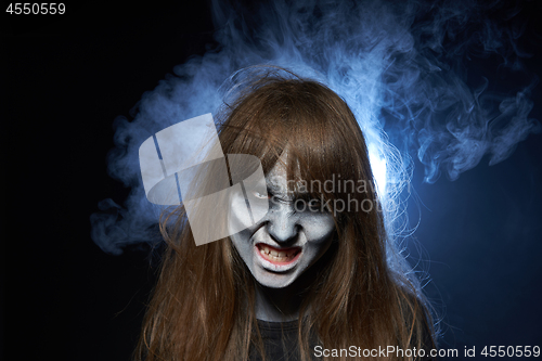 Image of A girl with zombie makeup over dark background with smoke and backlight