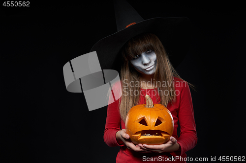 Image of Serious Halloween witch holding Jack O\'Lantern pumpkin looking at camera