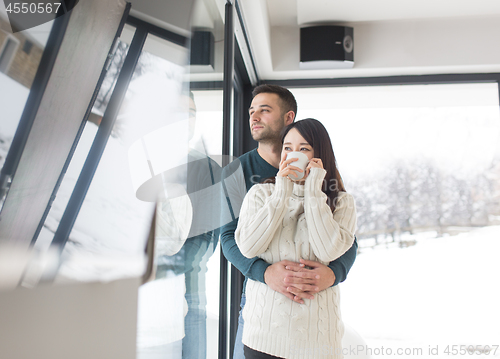 Image of multiethnic couple enjoying morning coffee by the window