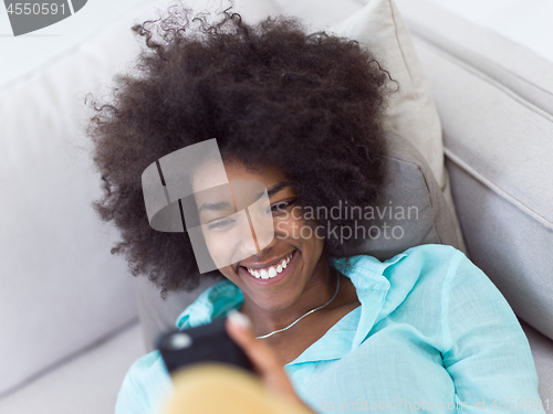 Image of black woman sitting on sofa and using mobile phone