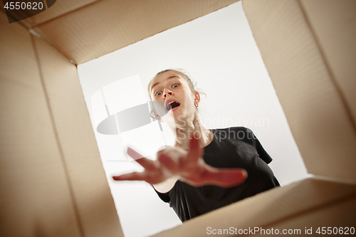 Image of Woman unpacking and opening carton box and looking inside