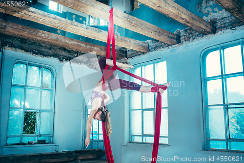 Image of Graceful gymnast performing aerial exercise at loft