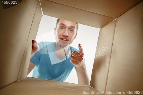 Image of Man smiling, unpacking and opening carton box and looking inside