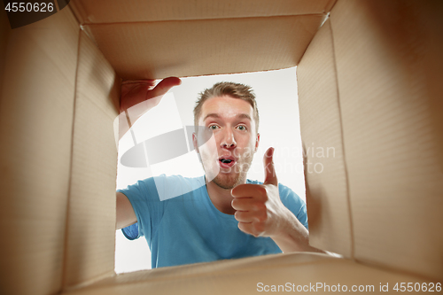 Image of Man smiling, unpacking and opening carton box and looking inside