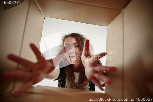 Image of Woman unpacking and opening carton box and looking inside