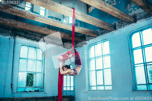 Image of Graceful gymnast performing aerial exercise at loft