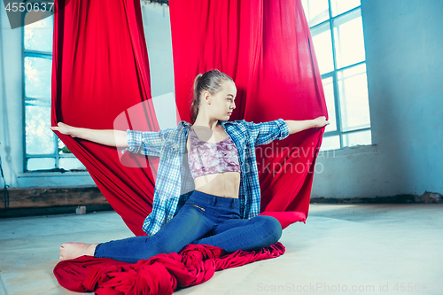 Image of Graceful gymnast resting after performing aerial exercise at loft