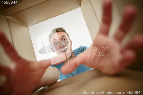 Image of Man smiling, unpacking and opening carton box and looking inside