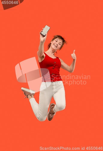 Image of Full length of pretty young woman with mobile phone while jumping