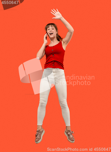 Image of Full length of pretty young woman with mobile phone while jumping