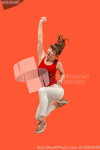 Image of Freedom in moving. Pretty young woman jumping against orange background