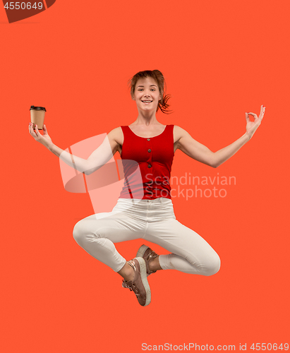 Image of Freedom in moving. Pretty young woman jumping against orange background