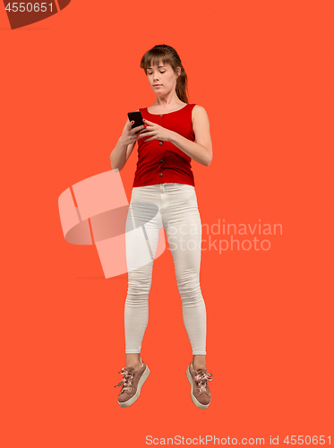 Image of Full length of pretty young woman with mobile phone while jumping