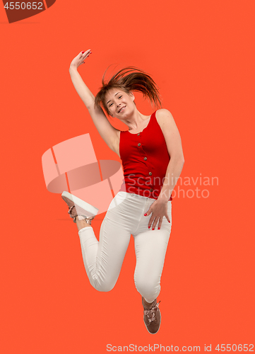 Image of Freedom in moving. Pretty young woman jumping against orange background