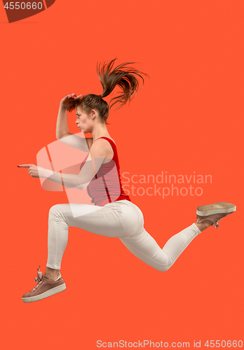 Image of Freedom in moving. Pretty young woman jumping against orange background