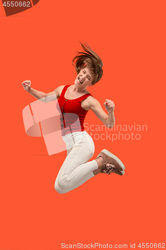 Image of Freedom in moving. Pretty young woman jumping against orange background