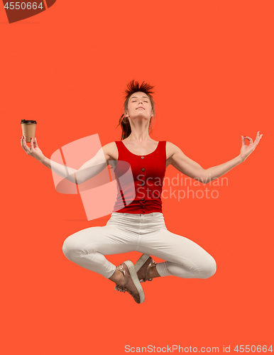 Image of Freedom in moving. Pretty young woman jumping against orange background