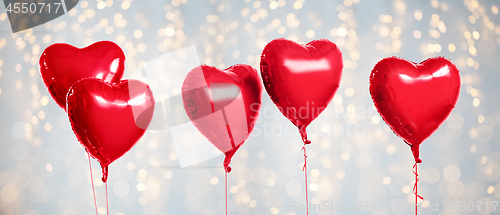 Image of five red heart shaped helium balloons on white