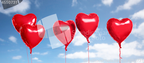 Image of five red heart shaped helium balloons on white