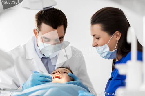 Image of dentist checking for kid teeth at dental clinic