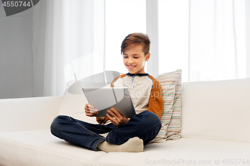 Image of smiling boy with tablet pc computer at home