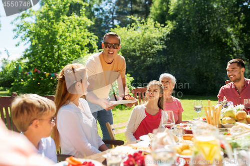 Image of family having dinner or barbecue at summer garden