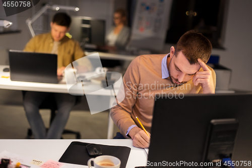 Image of man with computer working late at night office