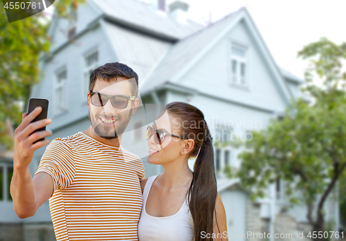 Image of couple taking selfie by smartphone over house