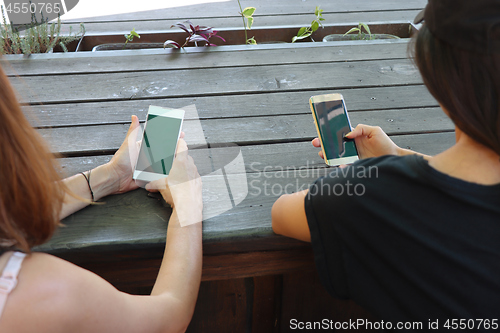 Image of Two young girls watching smart mobile phones