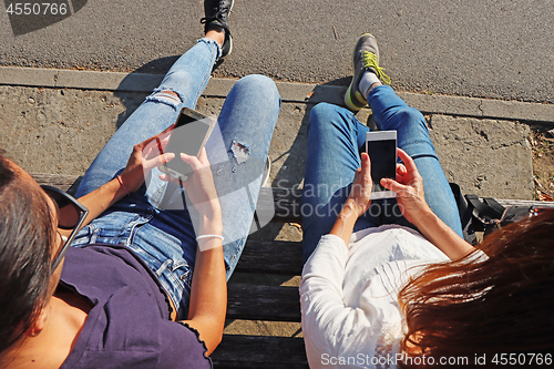 Image of Two young girls watching smart mobile phones