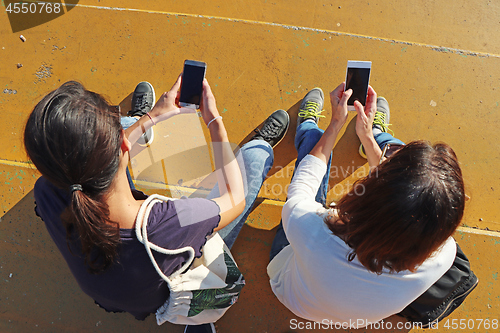 Image of Two young girls watching smart mobile phones