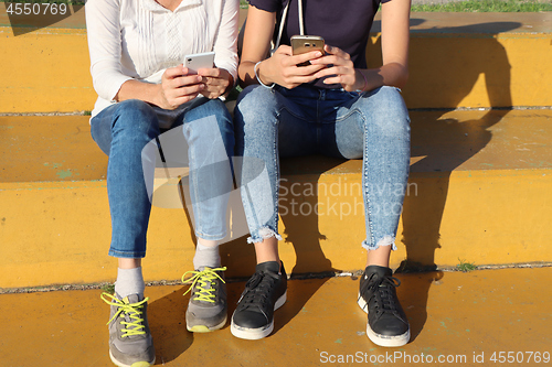 Image of Two young girls watching smart mobile phones