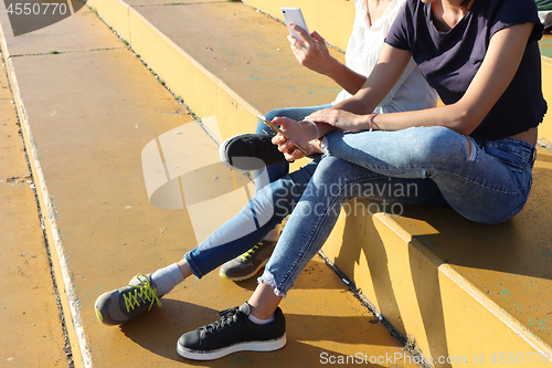 Image of Two young girls watching smart mobile phones