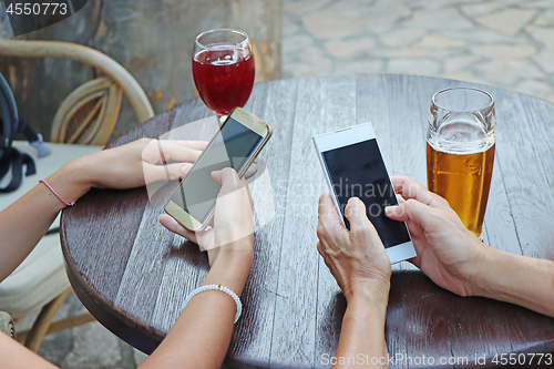 Image of Two young girls watching smart mobile phones