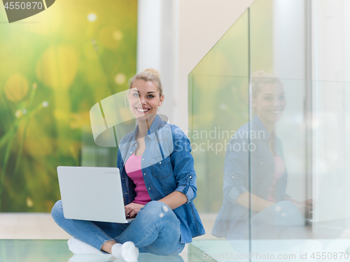 Image of young woman using laptop computer on the floor