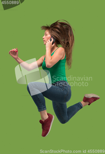 Image of Full length of pretty young woman with mobile phone while jumping