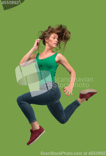 Image of Freedom in moving. Pretty young woman jumping against orange background