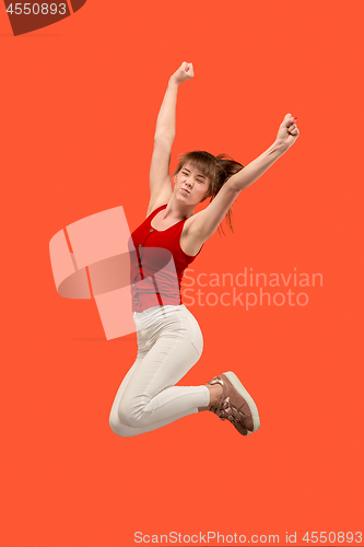 Image of Freedom in moving. Pretty young woman jumping against orange background