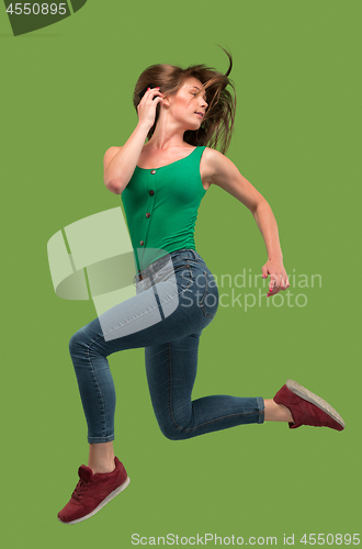 Image of Freedom in moving. Pretty young woman jumping against orange background