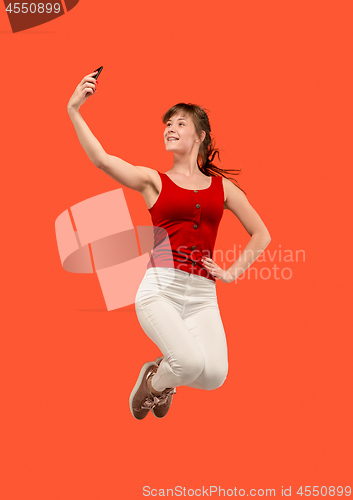 Image of Full length of pretty young woman with mobile phone while jumping