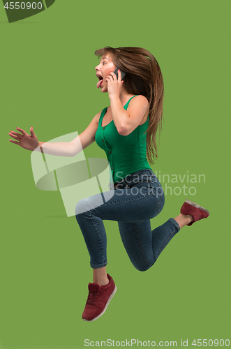 Image of Full length of pretty young woman with mobile phone while jumping