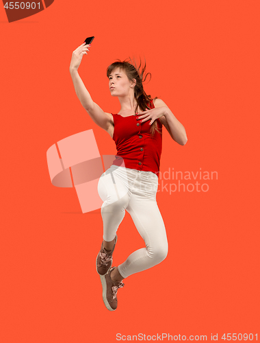 Image of Full length of pretty young woman with mobile phone while jumping