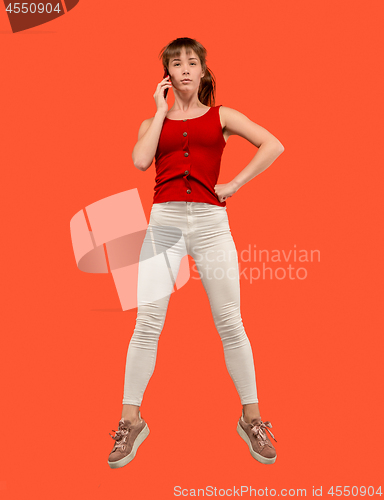 Image of Full length of pretty young woman with mobile phone while jumping