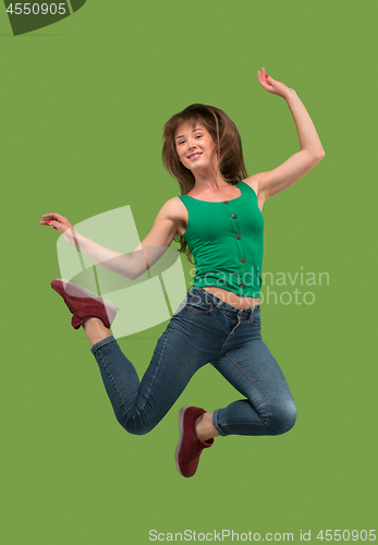 Image of Freedom in moving. Pretty young woman jumping against orange background